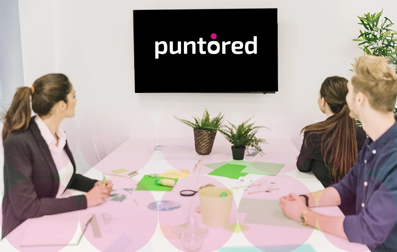 Grupo de ejecutivos viendo presentación de Puntored como opción líder en pagos digitales en pantalla grande